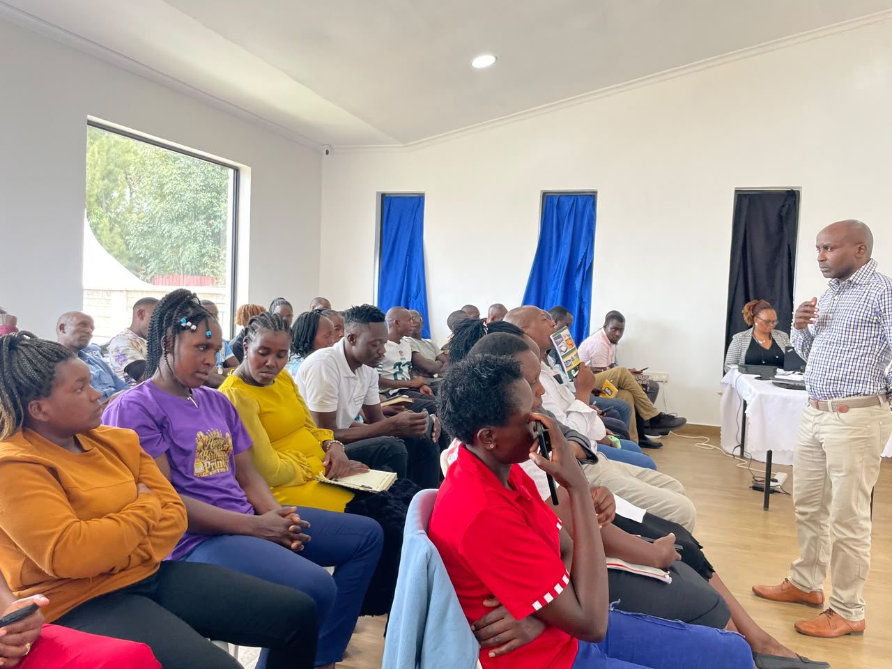 Faith Aid team members seated in a bright hall listening to a facilitator during a mental health awareness session